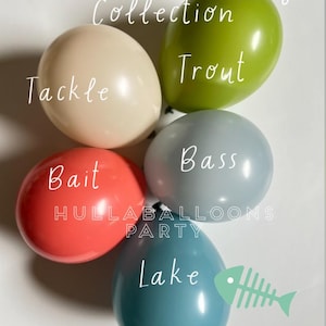 May include: A set of five balloons with fishing-themed words on them. The balloons are in the colors of teal, green, red, gray, and beige. The words on the balloons are "Tackle", "Trout", "Bass", "Bait", and "Lake".