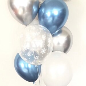 May include: A cluster of balloons in silver, blue, and white. Some balloons are clear with a snowflake pattern. The balloons are perfect for a winter-themed party.