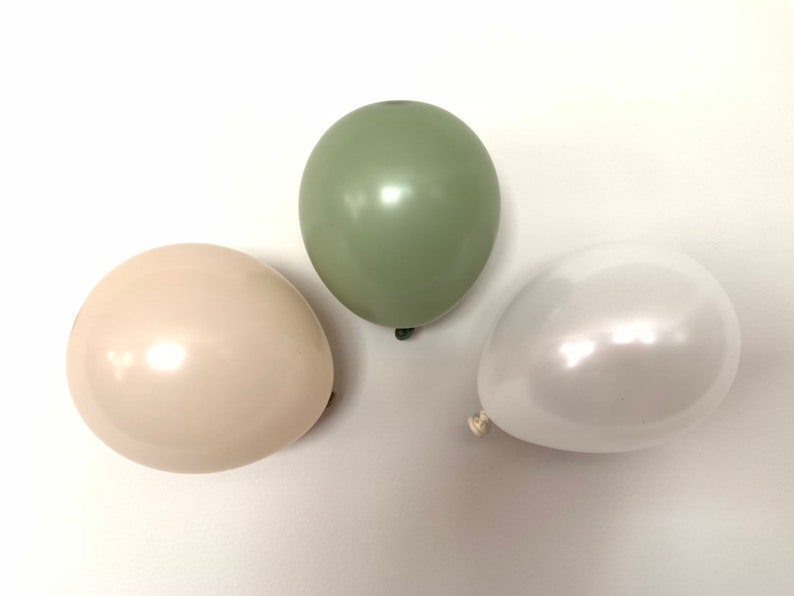 May include: Three latex balloons in different colors: sage green, cream, and white. The balloons are shiny and have a pearlescent finish.