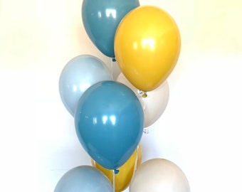 Könnte beinhalten: Ein Bündel Ballons in Blautönen, Gelb und Beige. Die Ballons sind zusammengebunden und bereit für eine Party oder Feier.