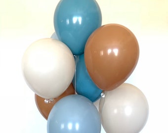 Könnte beinhalten: Ein Bündel Ballons in Blau, Braun und Creme. Die Ballons sind zusammengebunden und schweben in der Luft.