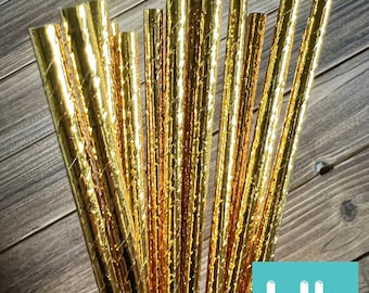 Könnte beinhalten: Ein Bündel goldfarbener Papierstrohhalme mit Streifen. Die Strohhalme sind etwa 20 cm lang und haben eine strukturierte Oberfläche.