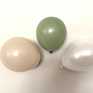May include: Three balloons in different colors: sage green, cream, and white. The balloons are all round and have a glossy finish.