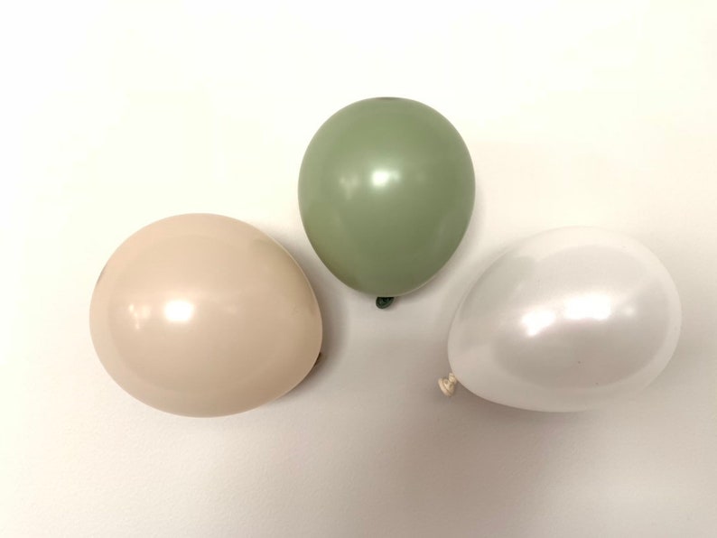 May include: Three balloons in different colors: sage green, cream, and white. The balloons are all round and have a glossy finish.