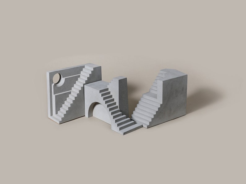 Puede incluir: Un conjunto de cuatro esculturas de hormig&oacute;n, cada una con un elemento arquitect&oacute;nico diferente, incluyendo escaleras, un arco y una abertura circular. Las esculturas est&aacute;n dispuestas en un patr&oacute;n geom&eacute;trico, creando un dise&ntilde;o moderno y abstracto.