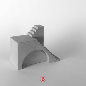 Puede incluir: Una escultura de hormig&oacute;n gris de un edificio con una escalera y un arco. La escultura est&aacute; sobre un fondo blanco.