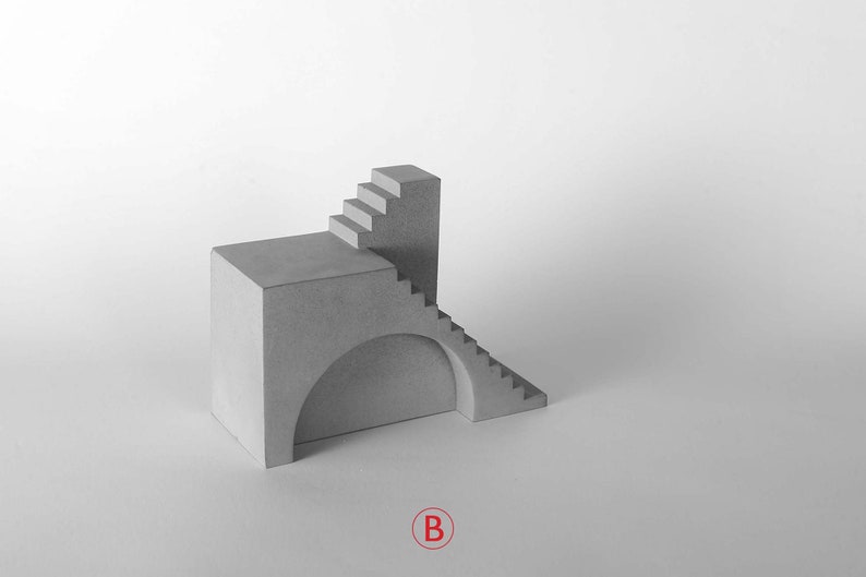 Puede incluir: Una escultura de hormig&oacute;n gris de un edificio con una escalera y un arco. La escultura est&aacute; sobre un fondo blanco.
