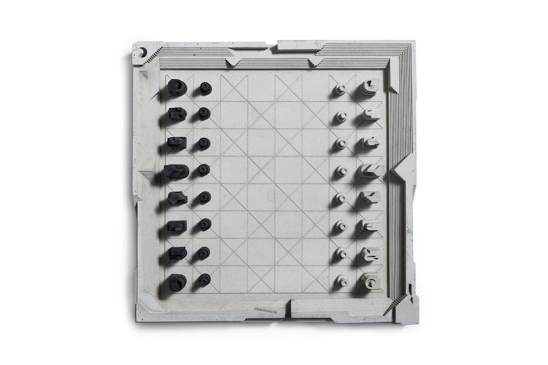 May include: A modern chess set with a gray board and black and white pieces. The board has a geometric design with a grid pattern. The chess pieces have a unique, abstract design. The set is displayed on a white background.
