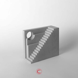 Puede incluir: Una escultura de hormig&oacute;n gris de un edificio con una escalera y una abertura circular. La escultura est&aacute; sobre un fondo blanco.