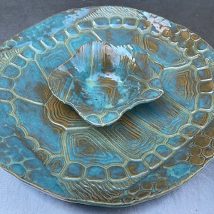 May include: A blue and brown ceramic serving dish with a smaller bowl attached. The dish has a textured surface that resembles a turtle shell.