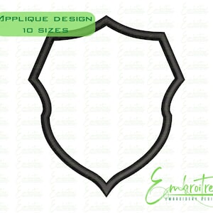 May include: Black shield-shaped applique design with a decorative border. The design is outlined in black and has a blank center. The text "APPLIQUE DESIGN 10 SIZES" is in a green rectangle at the top.