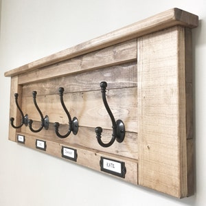 May include: A rustic wooden coat rack with four black metal hooks and personalized name tags. The tags read "Tim", "Joe", "Johnny", and "Kate".