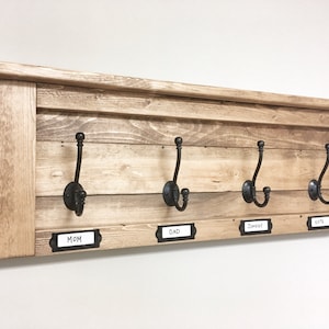 May include: Wooden coat rack with four black hooks and labels for "Mom", "Dad", "Johnny", and "Kate".