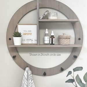 May include: A round wooden shelf with three shelves and hooks, painted in a classic grey stain. The shelf is 24 inches in diameter and features a sign that says "You are awesome".