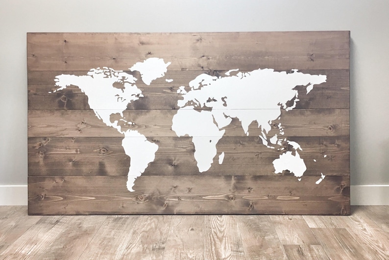 Pode incluir: Um mapa mundial branco pintado em uma placa de madeira marrom. O mapa &eacute; um contorno simples dos continentes e oceanos.
