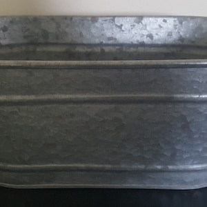 May include: A silver oval-shaped metal planter with a textured surface.
