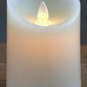 May include: A white pillar candle with a flickering LED flame. The candle is made of wax and has a realistic appearance.