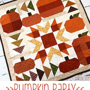 Pode incluir: Um cobertor de retalhos com um padrão de estrela no centro e abóboras ao redor da borda. O cobertor é feito com vários tecidos em tons de laranja, marrom, verde e branco. O cobertor mede 56 cm por 69 cm. O texto "Pumpkin Party" está escrito abaixo do cobertor.