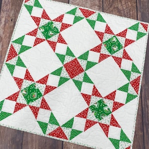 Peut inclure: Une courtepointe blanche avec un motif répétitif d'étoiles rouges et vertes. Les étoiles sont faites de tissu avec un fond blanc et un motif rouge et vert.