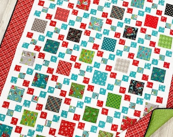 May include: A white quilt with a red and black plaid border. The quilt is made up of small squares of different fabrics with a Christmas theme. The squares are arranged in a checkerboard pattern.