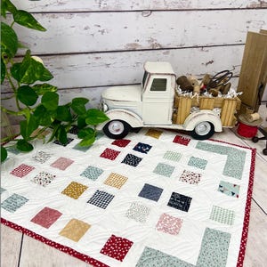 Puede incluir: Un patrón de colcha llamado "Primrose Cottage" diseñado por Lindsey Weight. La colcha está hecha de cuadrados de tela coloridos en una variedad de patrones y colores, incluyendo rojo, azul, verde, amarillo y blanco. La colcha mide 29 pulgadas por 22 pulgadas.