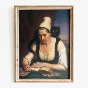 May include: A framed painting shows a woman in a white bonnet and dark vest, reading a book at a table. A black cat sits on her shoulder. Cards are scattered on the green tabletop. The artwork has a vintage aesthetic with a light-coloured wooden frame.
