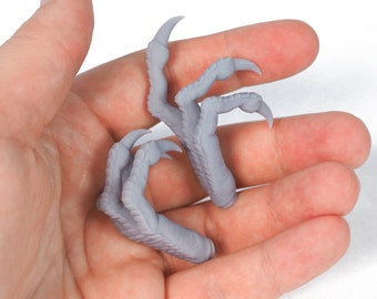 May include: Two gray 3D printed dinosaur claws with sharp points.