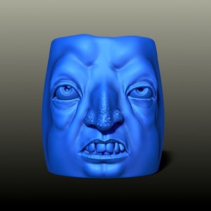 Può includere: Una scultura in 3D stampata in blu di un viso con un naso grande e una bocca larga. Il viso ha un'espressione scontrosa.