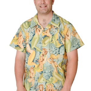 May include: A short-sleeved button-down shirt with a green and yellow pattern of mermaids. The shirt has a collared neckline and a button-up front.
