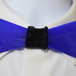 Könnte beinhalten: Eine blaue Fliege mit schwarzer Spitze. Die Fliege ist aus einem glatten, glänzenden Material gefertigt.