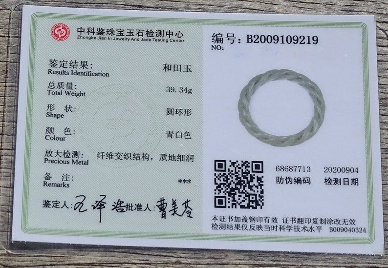 May include: A jadeite jade ring with a twisted rope design. The ring is light green in color and has a smooth, polished finish. The certificate shows the ring is 39.34 grams and has a round shape. The certificate number is B2009109219. The certificate also includes a QR code and a date of 20200904.