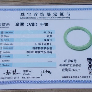 May include: A jadeite jade bracelet with a light green colour. The bracelet weighs 48.08 grams and has a certificate of authenticity with a unique identification number and a QR code. The certificate states that the bracelet is made of type A jadeite jade.
