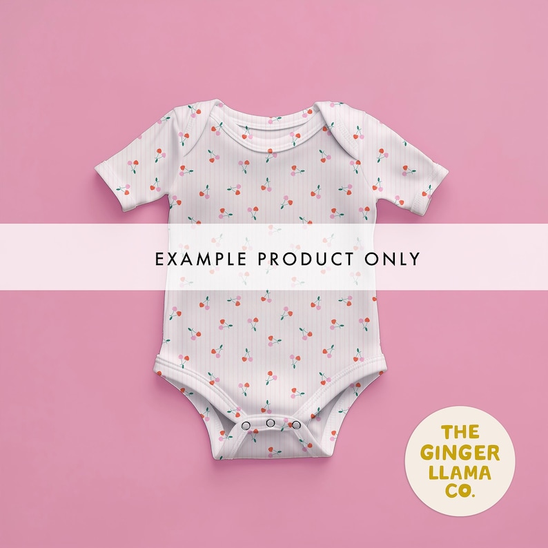 May include: White baby onesie with a pattern of red and pink cherries. The onesie has short sleeves and snaps at the bottom. The text "EXAMPLE PRODUCT ONLY" is across the front. A circular logo with the text "THE GINGER LLAMA CO." is in the bottom right corner.