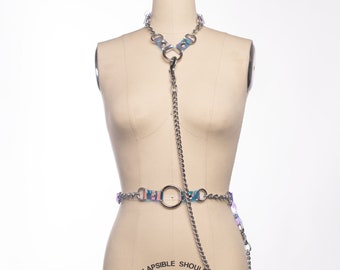 May include: A silver chain with iridescent blue and pink accents forms a choker and belt. The chain is connected by a large silver ring.