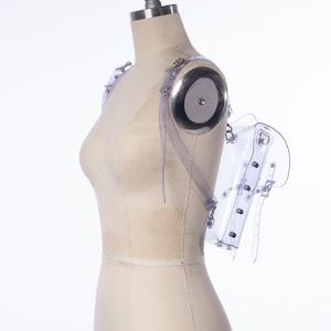 Puede incluir: Una mochila transparente de pl&aacute;stico con correas ajustables y hebillas plateadas. La mochila est&aacute; en un maniqu&iacute; blanco.