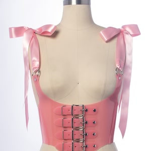 Pastel pink pvc buckle bodice with satin ribbon ties, displayed on a dress form.