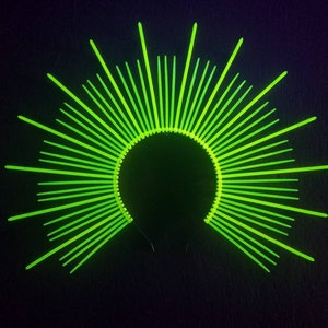 May include: A neon green headband with a circular design of radiating spikes. The headband is made of plastic and is perfect for a costume or party.