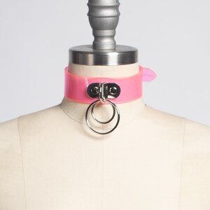 Peut inclure: Un collier ras de cou en plastique rose avec un anneau et un fermoir argent&eacute;s.