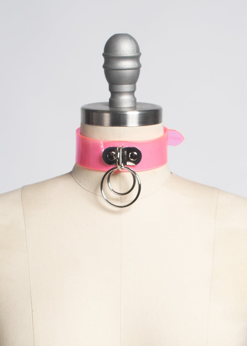 Peut inclure: Un collier ras de cou en plastique rose avec un anneau et un fermoir argent&eacute;s.