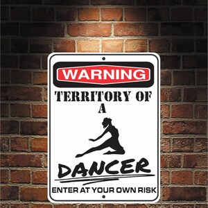 Puede incluir: Un cartel blanco con texto negro y una silueta negra de una bailarina. El cartel dice "Advertencia Territorio de una bailarina Entrar bajo su propio riesgo".