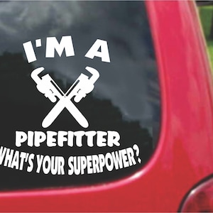 以下が含まれることがあります： 「I'm a Pipefitter What's Your Superpower?」というテキストと、交差したパイプレンチのペアが描かれた白いビニールステッカーです。