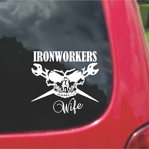 Puede incluir: Calcomanía de vinilo blanco con una calavera y llaves cruzadas. El texto "Ironworkers Wife" está debajo de la calavera.