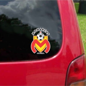 May include: A red, white, and yellow soccer team logo sticker with the words "Monarcas Morelia" on a red car.
