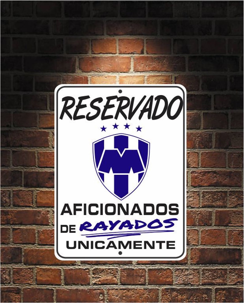 May include: A rectangular white sign with black text and a blue and white emblem. The sign reads "RESERVADO" above a shield-shaped logo and "AFICIONADOS DE RAYADOS UNICAMENTE" below. The sign is mounted on a brick wall.