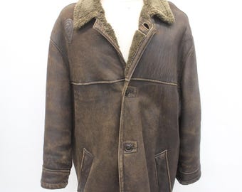 May include: A brown leather jacket with a shearling collar and button fastening. The jacket has two pockets on the front and a distressed look.