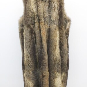 May include: A full-length, sleeveless fur vest in shades of brown and tan. The vest has a high collar and a textured, layered appearance. The fur appears to be thick and plush, with variations in color and pattern.