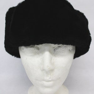 May include: A black faux fur hat with ear flaps. The hat is on a white mannequin head.