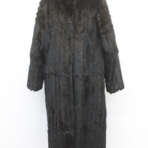 May include: Full-length black fur coat with a high collar. The coat has long sleeves and a textured appearance. The coat is displayed against a white background. The coat appears to be made of multiple panels.