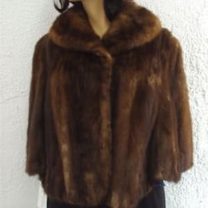 May include: A brown fur stole with a button fastening and a collar. The stole is made of a soft, luxurious fur.