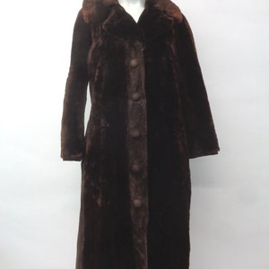 May include: A long brown faux fur coat with a collar and button fastening.